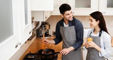 Cooking At Home. Smiling married couple preparing dinner, frying meal on pan, spending time together photo