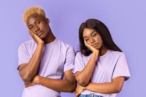 Bored African American couple with dull facial expressions on lilac background photo