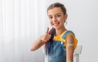 Effective Covid Vaccine Against New Delta Variant. Portrait Of Cheerful Smiling Adolescent Patient Showing Vaccinated Arm With Sticking Patch On Her Shoulder After Getting Shot And Thumb Up Gesture photo