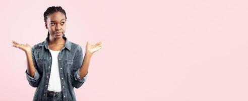 Choice Concept. Puzzled Black Lady Holding Two Invisible Objects Choosing Between Them Posing Over Pink Studio Background. Panorama, Empty Space photo