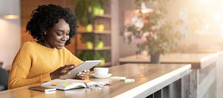 Cheerful african american businesswoman using digital tablet in cafe, working online, empty space photo