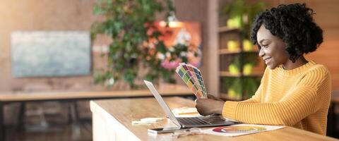 Black woman creative graphic designer working with color palette at cafe, using laptop, empty space photo