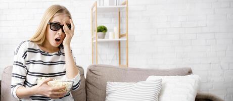 Frightened girl closing her eye with hand white watching 3d movie at home alone, using 3d glasses photo