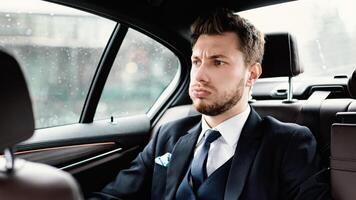 Got Stuck In A Traffic Jam. Annoyed worker sitting in the backseat of luxury car, being late photo