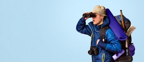 Backpacker looking through binoculars at free space, orange studio background photo