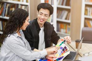 Two happy designers holding palette and choosing paint color from swatch catalog for interior design, copy space photo