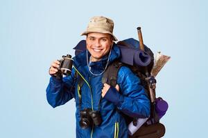 Hiker with binoculars smiling over orange studio background, panorama photo