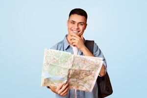 Positive guy making sightseeings, using city map over orange background photo