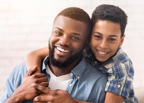 de cerca retrato de contento negro padre y su hijo abrazando y sonriente a cámara, posando a hogar juntos, selectivo enfocar, gratis espacio foto