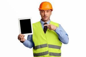 Surprised Worker Man Showing Tablet Empty Screen Advertising Building Services Standing On White Studio Background. Look Here. Mockup photo