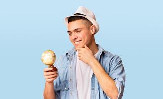 Excited tourist holding small globe, looking where to go next, orange background photo