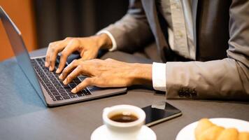 Server Developer. Close up of black man's hands typing on laptop keyboard, having breakfast at coffee shop photo