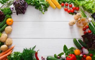 Frame of fresh organic vegetables on white wood background. Healthy natural food on table with copy space. Cooking ingredients top view, mockup for recipe or menu photo