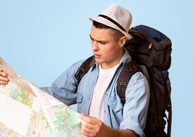 Close up of lost traveler with backpack looking at city map over orange background, empty space photo