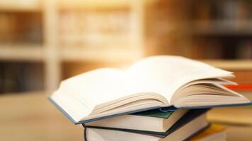Library Lovers Month. Side view of opened manual with blank pages lying on a stack of books on wood desk. Selective focus photo