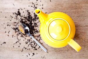 yellow teapot with spoon and tea photo