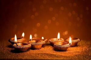 Four lit diya candles on a table with bokeh photo