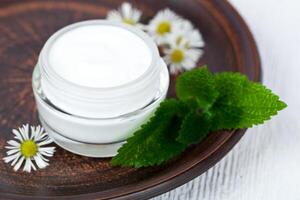container with cream urtica and chamomiles photo