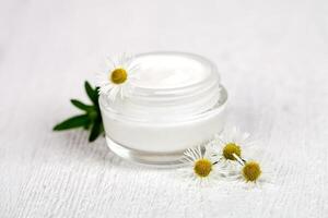 container with cream and chamomiles photo