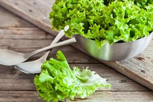 lettuce salad in metal bowl and spoons photo