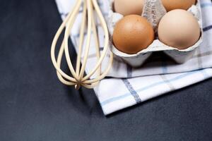 Eggs in cardboard box, towel and whisker closeup on backboard background. photo