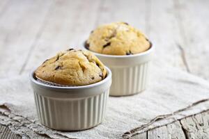 Homemade fresh muffins on ceramic white bowls on linen napkin. photo