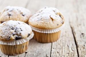 Homemade fresh muffins with sugar powder closeup on rustic wooden table background. photo