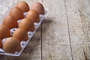 Fresh chicken eggs on plastic container on rustic wooden table background. photo