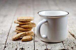 Cup of milk and stack of fresh baked oat cookies on rustic wooden table background. photo