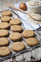Baking grid with fresh oat cookies on rustic wooden table background, ingredients and kitchen utensil closeup on rustic wooden table. photo