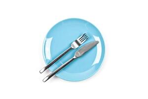 Set of empty blue plate, fork and knife on white background. photo