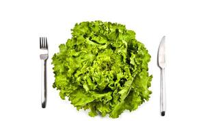 Organic green salad, fork and knife on white background. photo