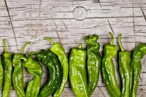 Fresh green raw peppers on rustic wooden table background. photo