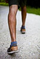 Low angle ground level view with feet of a man on park or forest path. photo