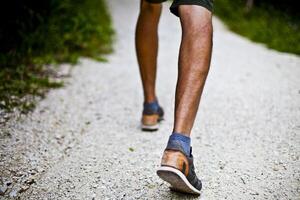 Low angle ground level view with feet of a man on park or forest path. photo