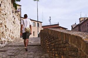Back view of a man tourist walking in ancient town. photo