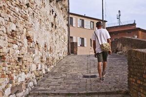 Back view of a man tourist walking in ancient town. photo
