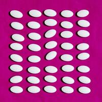White pills on pink background. photo