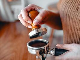 Close-up of hand Barista cafe making coffee with manual presses ground coffee using tamper at the coffee shop photo