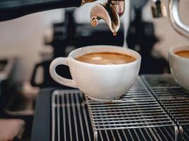 Coffee extraction from the coffee machine with a portafilter pouring coffee into a cup,Espresso poruing from coffee machine at coffee shop photo