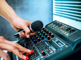Hand Sound engineer holding microphone on sound mixer in live broadcasting studio producer for sound record control system production and audio equipment and music instrument photo