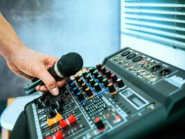 Hand Sound engineer holding microphone on sound mixer in live broadcasting studio producer for sound record control system production and audio equipment and music instrument photo