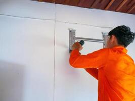 Air conditioning technicians Use an electric drill to drill into the wall to install the air conditioner base Prepare to install new air conditioner in homes. photo