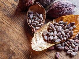 Close-up of brown cocoa beans on dry cocoa leaf and dry cacao pod on a rustic wooden table. photo