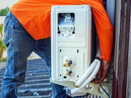 Air conditioning technicians install new compressor air in homes, Repairman fix air conditioning systems, Male technician service for repair and maintenance of air conditioners photo