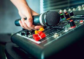 Hand Sound engineer holding microphone on sound mixer in live broadcasting studio producer for sound record control system production and audio equipment and music instrument photo