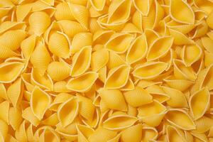 Uncooked Conchiglie Pasta. A Culinary Canvas of Conchiglie Macaroni, Creating a Lively and Textured Background for Gourmet Cooking. Dry Pasta. Raw Macaroni - Top View, Flat Lay photo