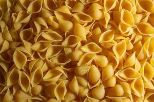 Uncooked Conchiglie Pasta. A Culinary Canvas of Conchiglie Macaroni, Creating a Lively and Textured Background for Gourmet Cooking. Dry Pasta. Raw Macaroni - Top View, Flat Lay photo