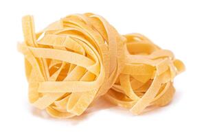 Two Classic Italian Raw Egg Fettuccine - Isolated on White Background. Dry Twisted Uncooked Pasta. Italian Culture and Cuisine. Raw Golden Macaroni Pattern - Isolation photo