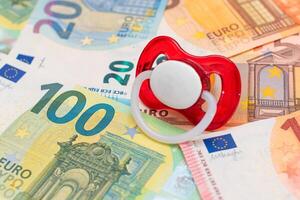 Childfree, Contraception and Birth Control Concept. Baby Pacifier on the Euro Banknotes. Having Children is Expensive and Unprofitable photo